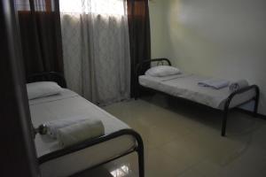 2 Betten in einem kleinen Zimmer mit Fenster in der Unterkunft Apartamentos Guzmán in Arenilla