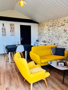 a living room with a yellow couch and chairs at L’Annexe in LʼÉpine
