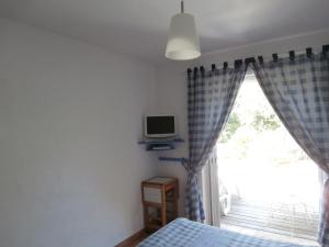 Un dormitorio con una cama y una ventana con un televisor. en La Mouchelière, en La Garde-Freinet