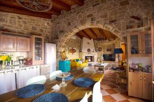 a kitchen and living room with a large stone wall at Stonehouse Olivelia - Afrathias Beach in Tympáki