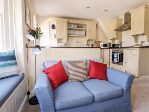 un sofá azul con 2 almohadas rojas en la cocina en Driftwood, en Fowey