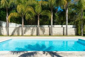 a blue swimming pool with palm trees in the background at TheCalming Cactus Cascais in Estoril