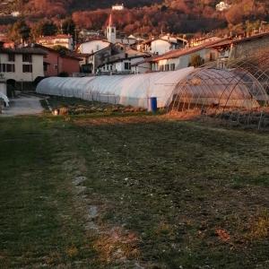 a field with a fence and a town with houses at Little Family in Salò
