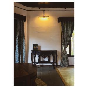 uma sala de estar com uma mesa num quarto com cortinas em Mulberry House em Almora