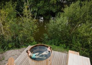 two people in a hot tub on a wooden deck at Huttopia Lac de Rillé in Rillé +35 photos