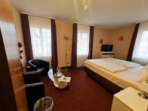 Hotel Am Schloss في آلتزي: غرفة نوم بسرير وطاولة وكرسي