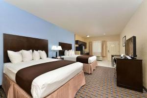 a hotel room with two beds and a flat screen tv at Western Inn & Suites in Carrizo Springs