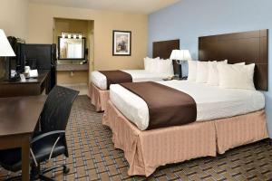 a hotel room with two beds and a desk and a desk at Western Inn & Suites in Carrizo Springs