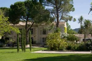 une grande maison avec des arbres dans la cour dans l'établissement Benvengudo, aux Baux-de-Provence