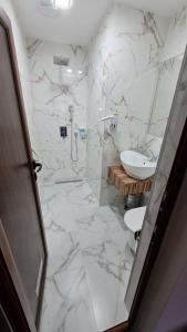 a bathroom with a sink and a white marble floor at Hotel Ponti in Vidin