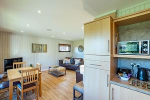eine Küche und ein Wohnzimmer mit einem Sofa und einem Tisch in der Unterkunft Birch Lodge in Newton Stewart