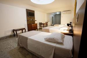 a hotel room with two beds and a table at Savassi Hotel in Belo Horizonte