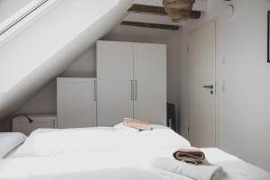 a white bedroom with two beds and white cabinets at Gulfhof Boomgaarden Boomgaarden 15 Reemt in Krummhörn