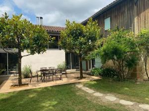 a patio with a table and chairs and trees at Majellon Grand Appartement in Sainte-Christie-dʼArmagnac +11 photos