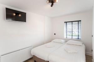 ein weißes Schlafzimmer mit 2 Betten und einem Fenster in der Unterkunft La Casa de Verano I in Zandvoort