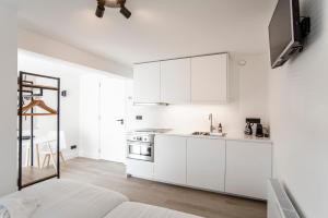 eine weiße Küche mit weißen Schränken und einem Tisch in der Unterkunft La Casa de Verano I in Zandvoort