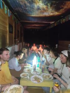 un grupo de personas sentadas alrededor de una mesa comiendo comida en Ella City Reach Hostel, en Ella