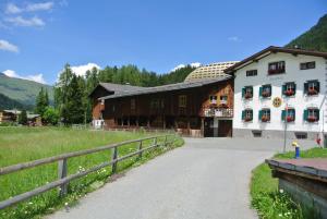a large white building with a fence next to a field at Pension Hof zur Stilli in Davos