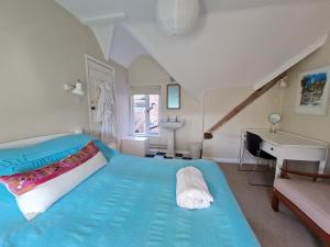 溫徹斯特的住宿－Beggar's Lane Cottage，一间卧室配有一张蓝色的床、一个水槽和一张书桌