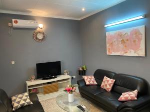 sala de estar con muebles de cuero negro y TV de pantalla plana en Studio de haut standing, Bonamoussadi (Kotto), en Douala