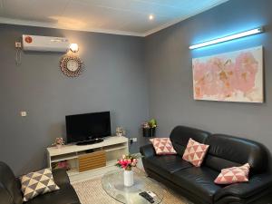 a living room with black leather furniture and a flat screen tv at Studio de haut standing, Bonamoussadi (Kotto) in Douala