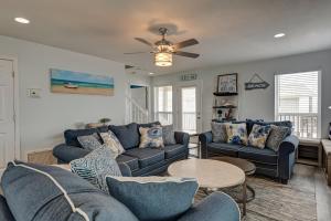 a living room with blue couches and a ceiling fan at Strand Castle - GULF FRONT! An ideal layout with game room, small private pool, and roof top crow's nest! home in Dauphin Island