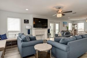 a living room with two blue couches and a tv at Strand Castle - GULF FRONT! An ideal layout with game room, small private pool, and roof top crow's nest! home in Dauphin Island
