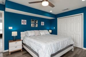 a blue bedroom with a bed and a white door at Strand Castle - GULF FRONT! An ideal layout with game room, small private pool, and roof top crow's nest! home in Dauphin Island