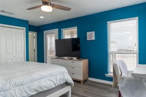 a bedroom with blue walls and a bed and a tv at Strand Castle - GULF FRONT! An ideal layout with game room, small private pool, and roof top crow's nest! home in Dauphin Island