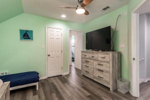 a bedroom with a flat screen tv and a dresser at Strand Castle - GULF FRONT! An ideal layout with game room, small private pool, and roof top crow's nest! home in Dauphin Island
