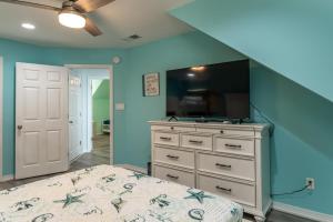 a bedroom with a bed and a tv on a dresser at Strand Castle - GULF FRONT! An ideal layout with game room, small private pool, and roof top crow's nest! home in Dauphin Island