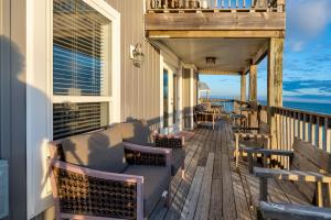 a porch with chairs and tables on a house at Strand Castle - GULF FRONT! An ideal layout with game room, small private pool, and roof top crow's nest! home in Dauphin Island