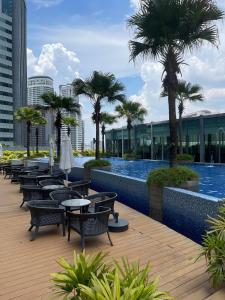 una fila de mesas y sillas junto a una piscina en Vortex Suites KLCC by Luna en Kuala Lumpur