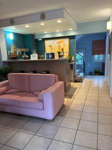 a living room with a pink couch and a bar at Mira Mare Hotel, Galaxidi in Galaxidi