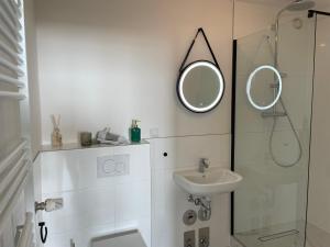 ein weißes Badezimmer mit einem Waschbecken und einem Spiegel in der Unterkunft Weser-Traum in Bremerhaven