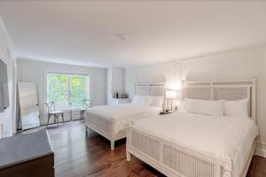 a white bedroom with two beds and a desk at Kent Island Resort in Stevensville
