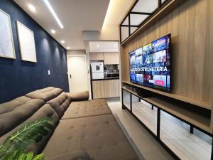 a living room with a large flat screen tv at Apto amplo Aconchegante 3Qts, TV 65, Ar Cond Ótima localização in Maringá