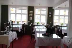 a dining room with tables and chairs and windows at Hotel Framtid in Djúpivogur +37 photos