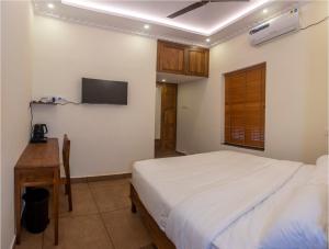 Ekana Homes في تريفاندروم: غرفة نوم بسرير وتلفزيون على الحائط