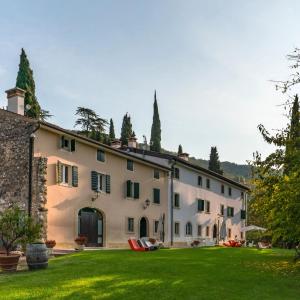 an exterior view of a large white building with a yard at Massimago Wine Relais in Mezzane di Sotto