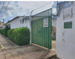 a green door with a sign on it next to a building at Suíte 08 - Aconchegante e Exclusiva in Cuiabá