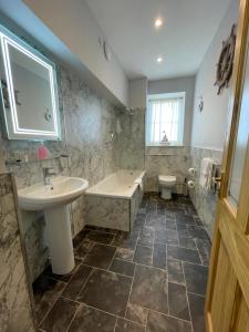 a bathroom with a sink and a tub and a toilet at Chandlers BnB in Seahouses