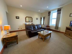a living room with a leather couch and a table at Chandlers BnB in Seahouses