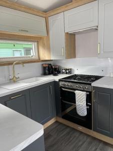 a kitchen with a black stove and white cabinets at Swift Bordeaux in Dunoon