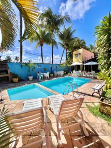 ein Pool mit zwei Gartenstühlen und ein Resort in der Unterkunft Pousada Bon Vivant in Porto De Galinhas