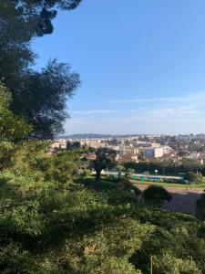 a view of a city from a hill with trees at Studio with a panoramic view at the last floor of the residence with a pool in Antibes