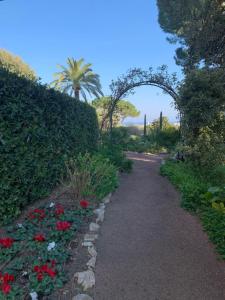 a path through a garden with flowers and an arch at Studio with a panoramic view at the last floor of the residence with a pool in Antibes