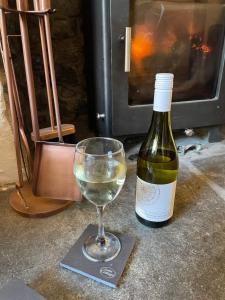 una copa de vino blanco junto a una botella de vino en Lotte’s Cottage, en Bideford
