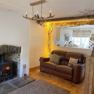 sala de estar con sofá de cuero y chimenea en Lotte’s Cottage, en Bideford