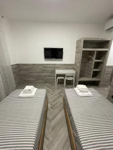 een kamer met twee bedden en een tafel en een televisie bij Holiday Rooms Rho in Rho
